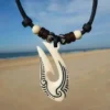 Collar Maori Hei Matau de hueso tallado, símbolo de protección y conexión con el océano.
