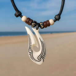 Collar Maori Hei Matau de hueso tallado, símbolo de protección y conexión con el océano.