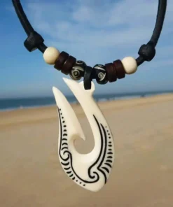 Collar Maori Hei Matau de hueso tallado, símbolo de protección y conexión con el océano.