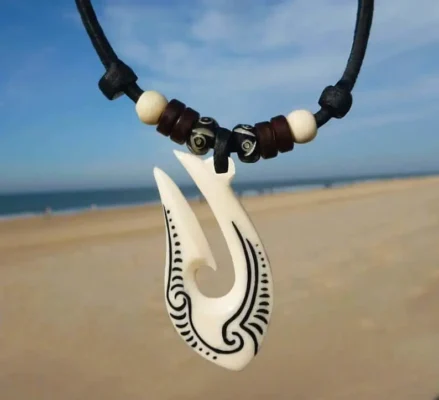 Collar Maori Hei Matau de hueso tallado, símbolo de protección y conexión con el océano.