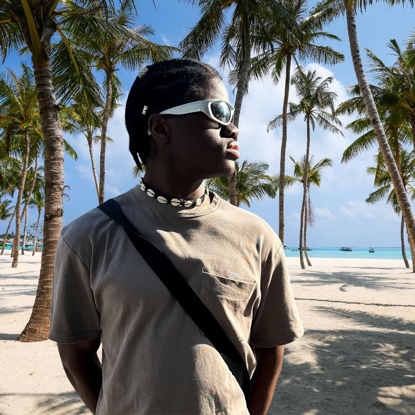 Hombre con Collar de Conchas Hombre; cuero trenzado y cauri, estilo surfer, luz natural.