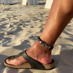 Tobillera de cuero artesanal con calavera en la playa estilo surfista